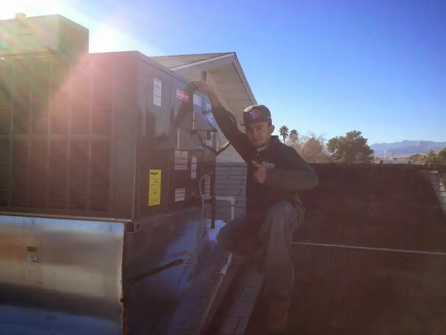 HVAC technician performing Heat Pump Repair on a rooftop unit in Tuscaloosa